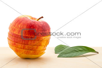 apple preserved its shape, but cut into slices and two leaves on a wooden table.
