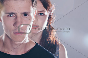 Cropped image of beautiful couple looking at each other and smiling while standing straight on gray background