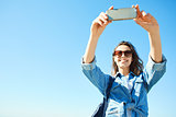 portrait of a young attractive woman using phone on the blue sky background