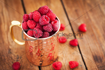 Fresh ripe raspberries in a copper mug