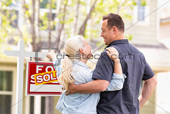 Caucasian Couple Facing and Pointing to Front of Sold Real Estat