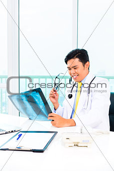 Asian doctor examining x-ray picture in practise