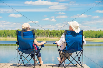 view from the back of a couple on chairs relaxes near a lake on 
