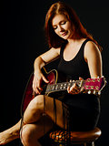 Beautiful redhead woman playing acoustic guitar