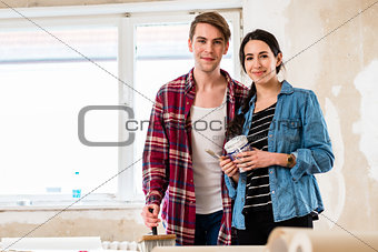 Portrait of a happy young couple holding tools for home remodeling