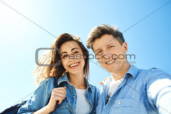 happy smiling couple, attractive man and woman looking in the camera at the sky background.
