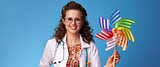 smiling pediatrician doctor showing colorful windmill on blue