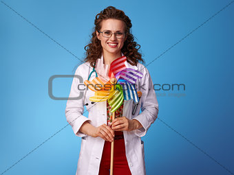 happy pediatrist doctor with colorful windmill on blue