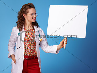 smiling paediatrician woman looking at placard on blue