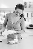 Happy young woman pouring milk into glass