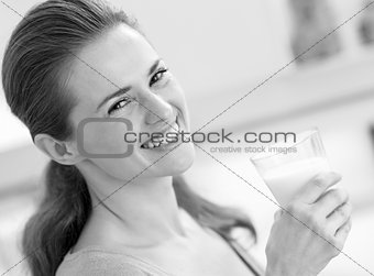 smiling young woman with glass of milk in kitchen