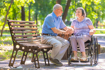 Elderly man strengthens his wife in the wheelchair 