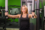 Woman doing fitness training on a butterfly machine with weights in a gym