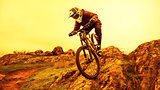 Professional Cyclist Riding Mountain Bike Down the Rocky Hill. Extreme Sport and Enduro Biking Concept.