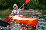 Young Woman Paddling Kayak on Beautiful River or Lake among Stones at the Evening