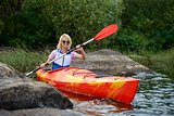 Young Woman Paddling Kayak on Beautiful River or Lake among Stones at the Evening