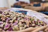 Background of basket of pistachios without shells on market, selective focus