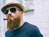 Bearded man with sunglasses smoking a cigar