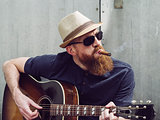 Bearded man playing acoustic guitar and smoking cigar