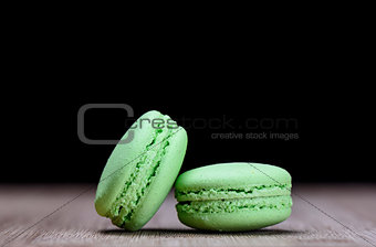 Two green macaroons on wooden table