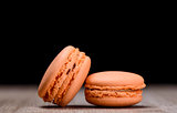 Two orange macaroons on wooden background