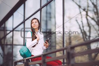 A teenage girl with a smartphone in her hands spends time outdoors