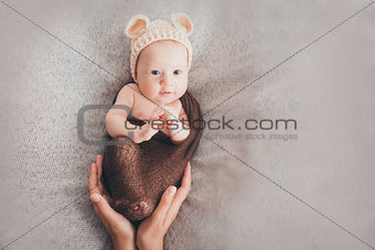 Light-eyed smiling baby. A little child in a beige cap with ears