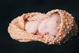 newborn baby lying on a black background. Imitation of a baby in the womb. beautiful little girl sleeping lying on her tummy.