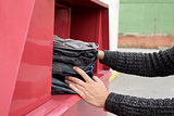 man depositing used clothes in a clothing bin