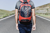 young backpacker man walking by a secondary road