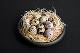 some quail eggs in a black ceramic bowl
