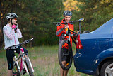 Young Couple Unmounting Mountain Bikes from Bike Rack on the Car. Adventure and Family Travel Concept.