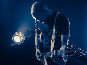 Guitar player in front of spotlight blue tone