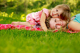 mother with her little daughter lie on the grass