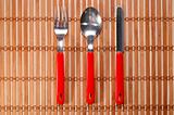 Spoon, fork and knife on bamboo background