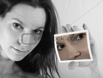 Pretty young woman holding a Polaroid showing part of her face
