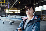 Confident female pilot posing in the hangar