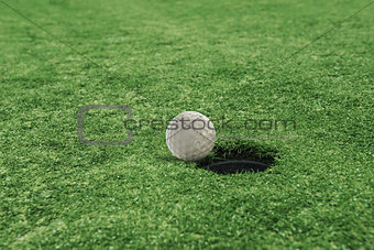 Golf ball near the hole in a grass field