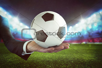 Sport bets. Soccer ball on the hand of a businessman with stadium background