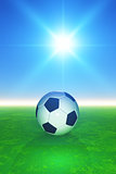 3D football on grassy pitcch against sunny blue sky