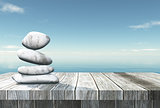 3D balancing pebbles on a wooden table looking out to the ocean