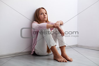 Young teenager girl sitting on the floor by the wall - looking a