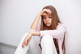 Young teenager girl having a heartache - sitting on the floor by
