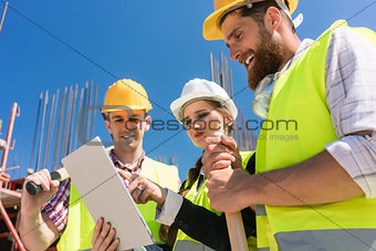 Architect or manager showing to her colleagues electronic building plan