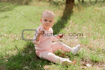 the child sits on the grass and holds two cones looking at the c