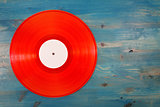 Red vinyl record on blue wooden background