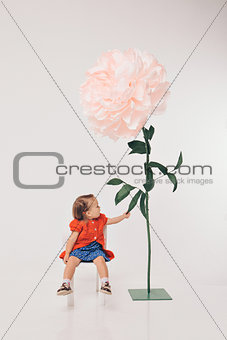 Big flower and little girl in red on white background