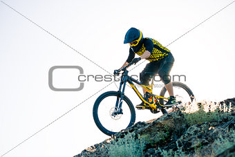 Cyclist Riding the Mountain Bike on the Summer Rocky Trail at the Evening. Extreme Sport and Enduro Cycling Concept.