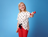happy modern child in red pants on blue showing dumbbell