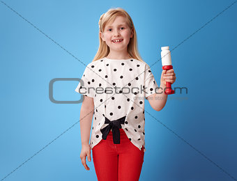 happy modern child showing dumbbell and pills bottle on blue